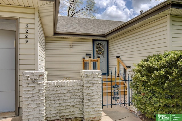 entrance to property featuring a gate, roof with shingles, and fence