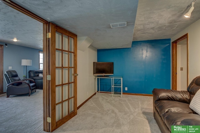 carpeted living room with a textured ceiling, visible vents, and baseboards