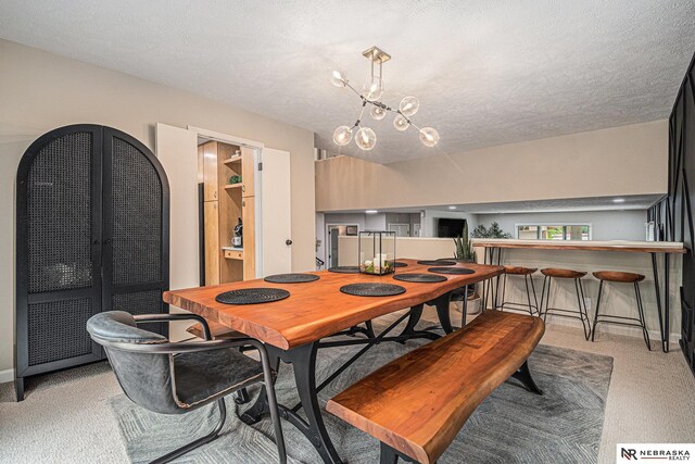 carpeted dining room featuring an inviting chandelier and a textured ceiling