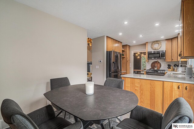 kitchen featuring appliances with stainless steel finishes, a sink, light countertops, a peninsula, and recessed lighting