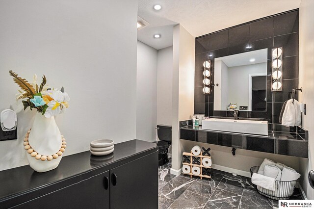 bathroom featuring recessed lighting, a sink, and marble finish floor