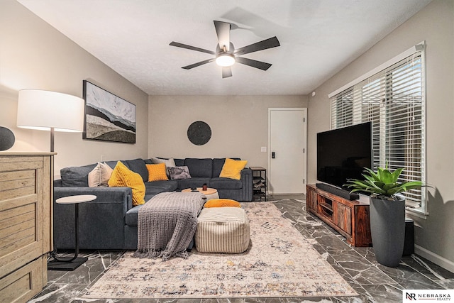 living area featuring a ceiling fan, baseboards, and marble finish floor