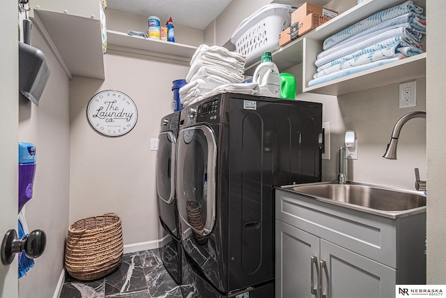 clothes washing area with marble finish floor, baseboards, washing machine and clothes dryer, a sink, and cabinet space