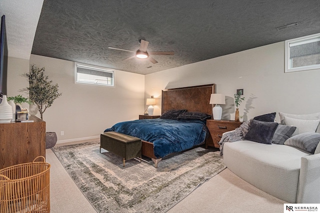 carpeted bedroom featuring baseboards, ceiling fan, and a textured ceiling
