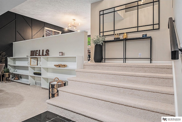 stairway featuring an inviting chandelier, carpet, and a textured ceiling
