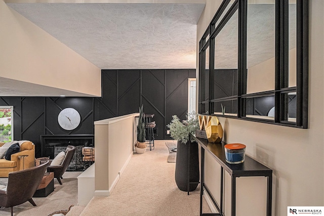 hallway with carpet flooring, a textured ceiling, and a decorative wall