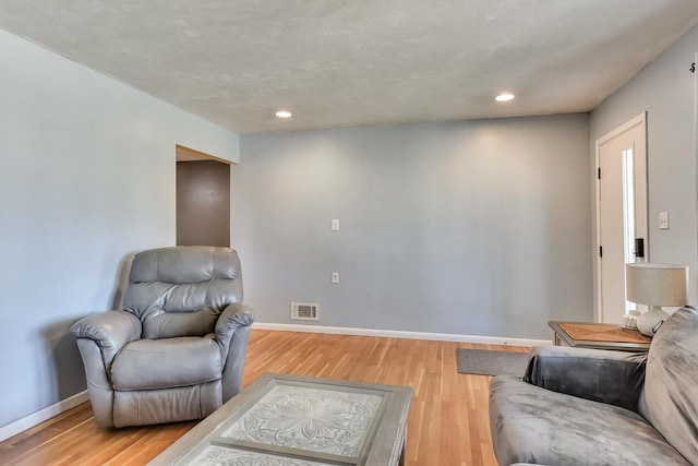 living room featuring light wood-style floors, baseboards, recessed lighting, and visible vents