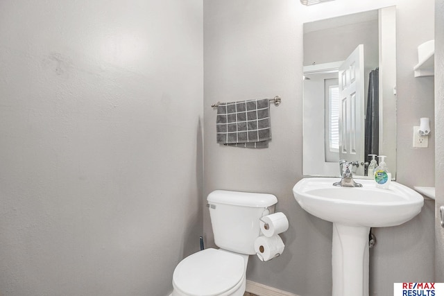bathroom with baseboards and toilet