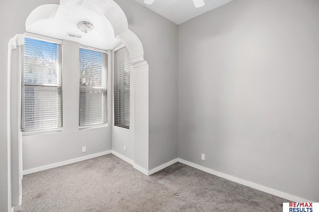 spare room with carpet floors, baseboards, ceiling fan, and visible vents