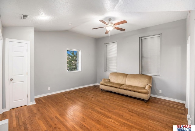 living area with baseboards, ceiling fan, wood finished floors, and vaulted ceiling