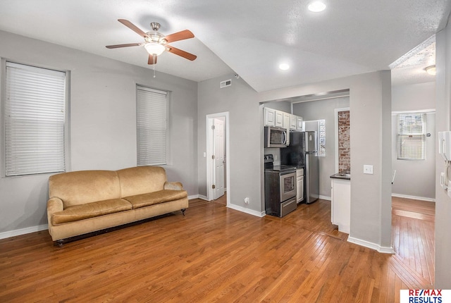 living area featuring light wood-type flooring, baseboards, and ceiling fan