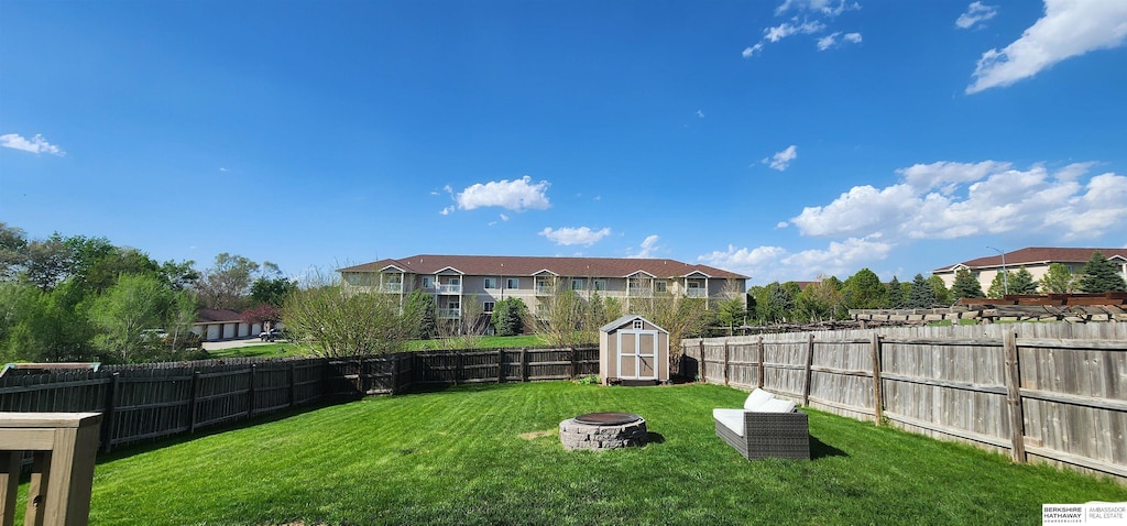 view of yard with a storage unit, a fenced backyard, an outdoor fire pit, and an outbuilding