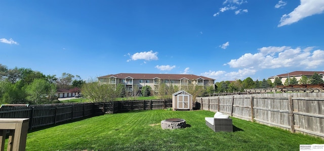 view of yard with a storage unit, a fenced backyard, an outdoor fire pit, and an outbuilding