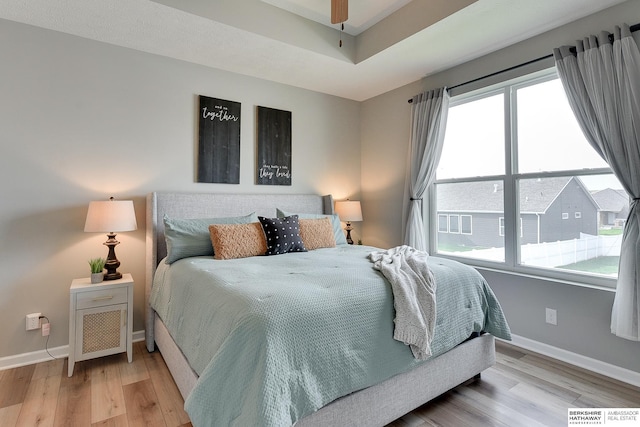 bedroom with baseboards, multiple windows, and light wood finished floors