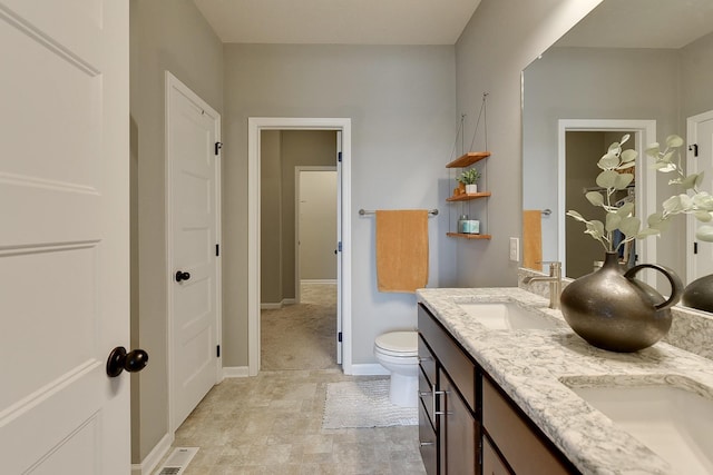full bathroom featuring double vanity, visible vents, a sink, baseboards, and toilet
