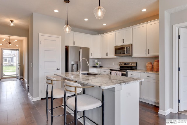 kitchen with white cabinets, a sink, stainless steel appliances, dark wood-type flooring, and backsplash