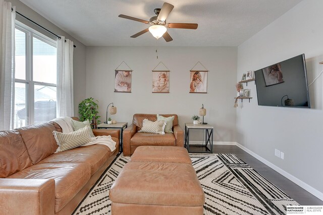 living area featuring baseboards, ceiling fan, and wood finished floors