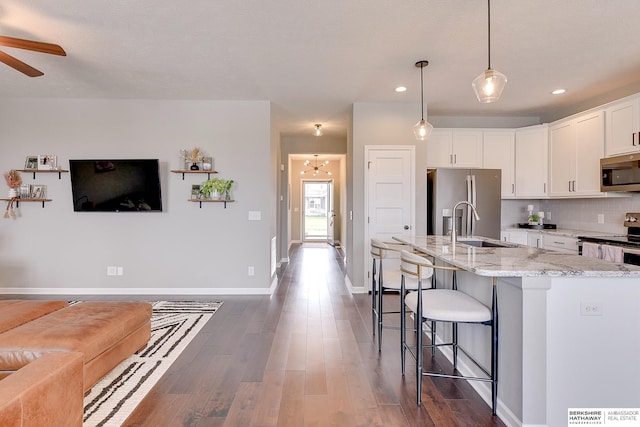 kitchen with appliances with stainless steel finishes, white cabinets, ceiling fan with notable chandelier, and dark wood finished floors