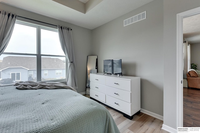 bedroom with baseboards, visible vents, and light wood-style floors