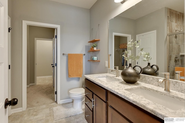 bathroom with double vanity, a sink, toilet, and tiled shower
