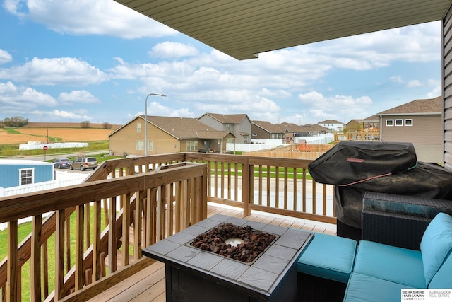 wooden terrace featuring fence, a residential view, and an outdoor fire pit