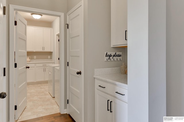 clothes washing area featuring cabinet space, light wood finished floors, and independent washer and dryer