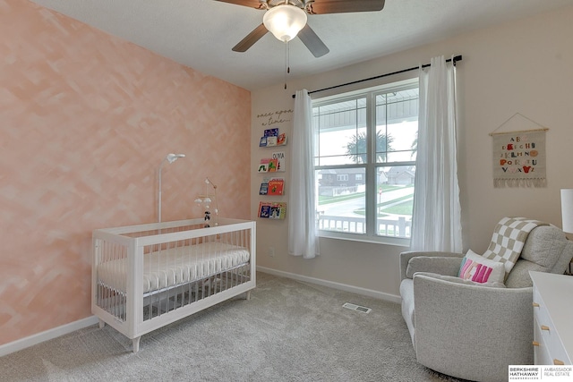carpeted bedroom with a nursery area, baseboards, visible vents, and a ceiling fan