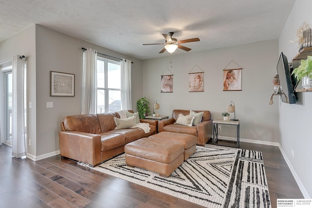 living area with a textured ceiling, ceiling fan, dark wood-style floors, and baseboards