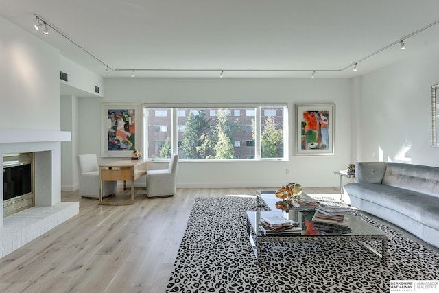 living area featuring visible vents, track lighting, wood finished floors, and a fireplace