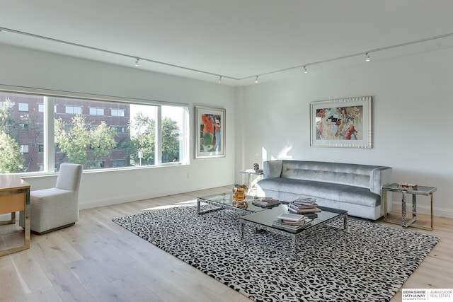 living area with track lighting, baseboards, and wood finished floors