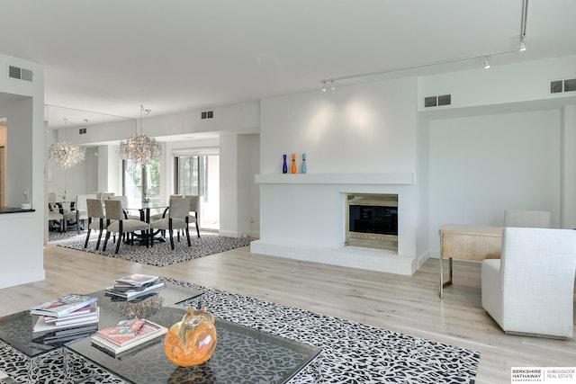 living area featuring rail lighting, wood finished floors, and visible vents
