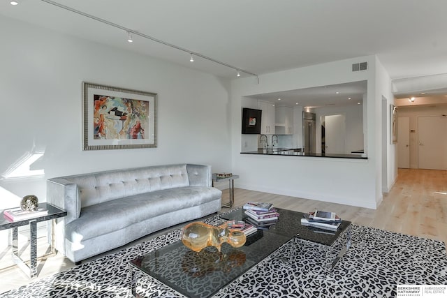 living room featuring visible vents, rail lighting, baseboards, and wood finished floors