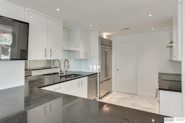 kitchen with a sink, appliances with stainless steel finishes, white cabinetry, and marble finish floor