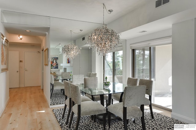 dining area with visible vents, light wood finished floors, and an inviting chandelier