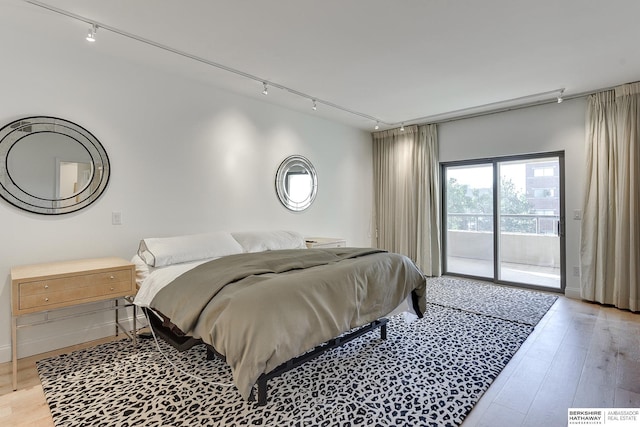 bedroom with access to outside, rail lighting, and light wood-style flooring
