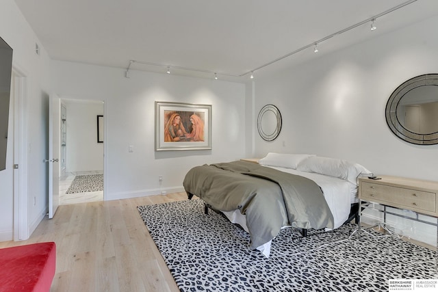 bedroom featuring baseboards, visible vents, track lighting, and light wood-style floors
