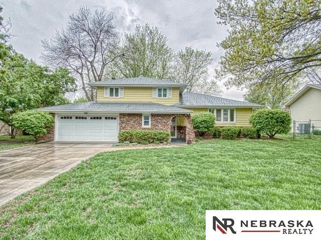 tri-level home with brick siding, fence, driveway, and a front yard