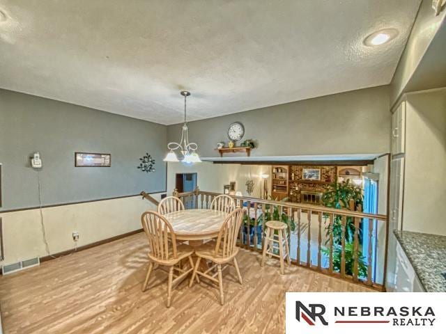 dining area with a textured ceiling, wood finished floors, and visible vents