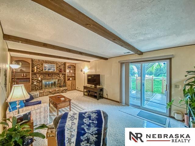 carpeted living room featuring built in features, beamed ceiling, and a textured ceiling