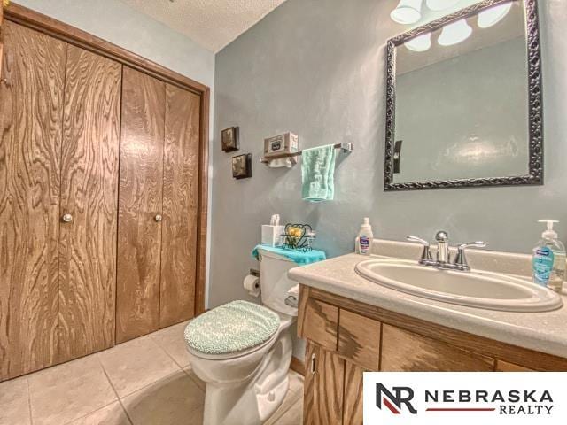 bathroom featuring vanity, a textured ceiling, tile patterned floors, and toilet