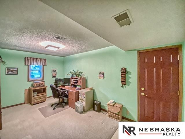 office space with visible vents, a textured ceiling, carpet floors, and baseboards