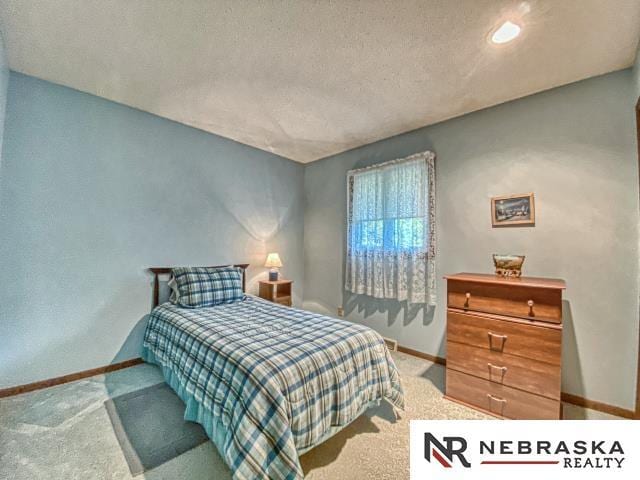 carpeted bedroom featuring baseboards and a textured ceiling