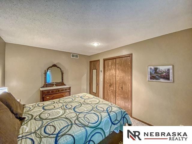carpeted bedroom with visible vents, a textured ceiling, and a closet