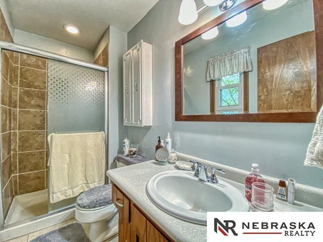 bathroom with vanity, recessed lighting, toilet, and a shower stall