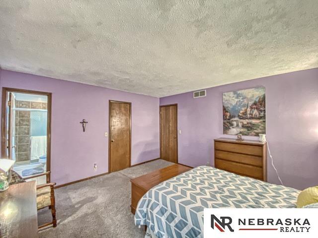 carpeted bedroom featuring a textured ceiling and visible vents