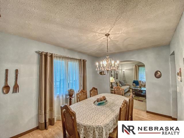 dining space featuring arched walkways, baseboards, a notable chandelier, and light wood-type flooring