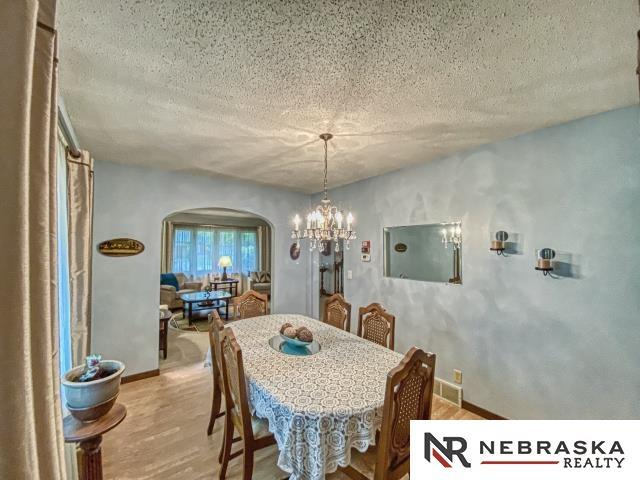 dining space with an inviting chandelier, arched walkways, a textured ceiling, and wood finished floors