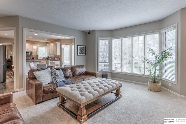 living room with light colored carpet, recessed lighting, baseboards, and a textured ceiling