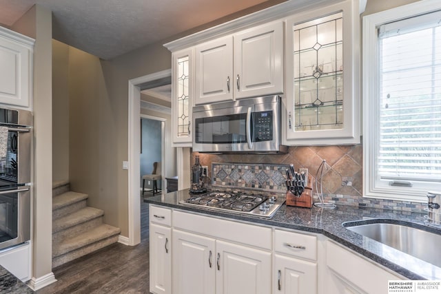 kitchen featuring dark wood-style flooring, stainless steel appliances, white cabinetry, and decorative backsplash