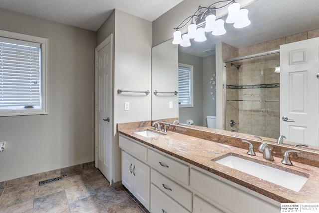 full bathroom featuring toilet, baseboards, a sink, and a stall shower
